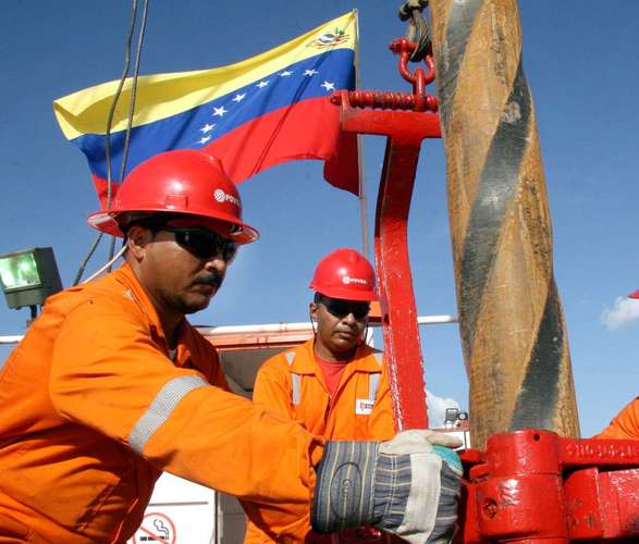 Oil field workers operating drilling equipment with Venezuelan flag